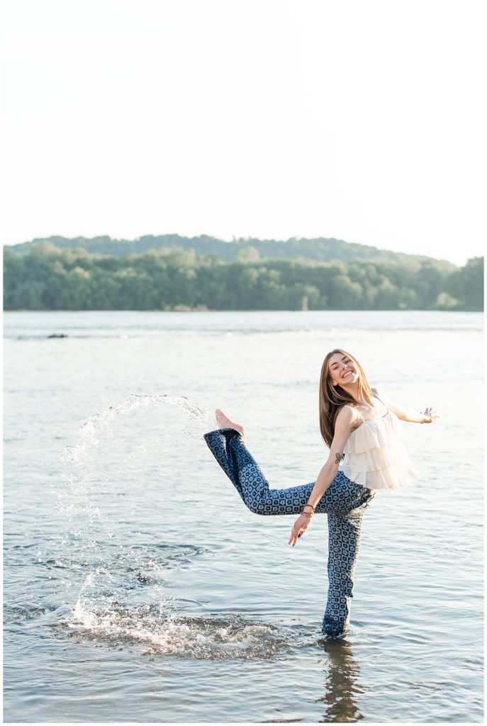 senior girl kicking her right leg back gracefully and making a splash in the susquehanna river at the white cliffs of conoy on sunny evening