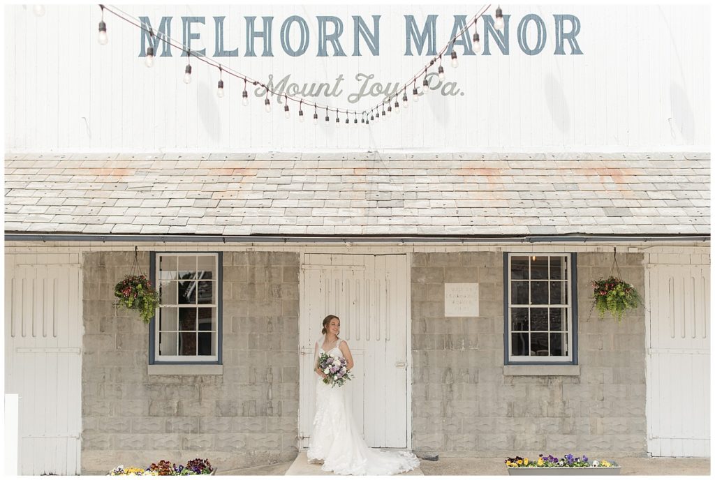 bride standing in front of white barn door holding bouquet in mount joy pennsylvania at melhorn manor
