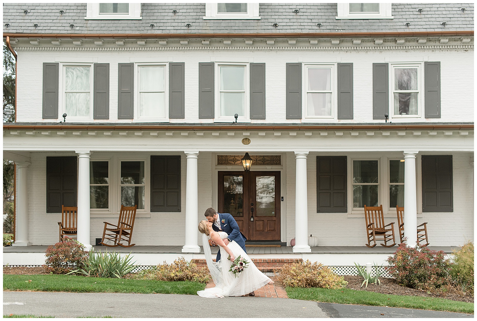 groom dips back his bride kissing her in front of large farmhouse at historic ashland in york county