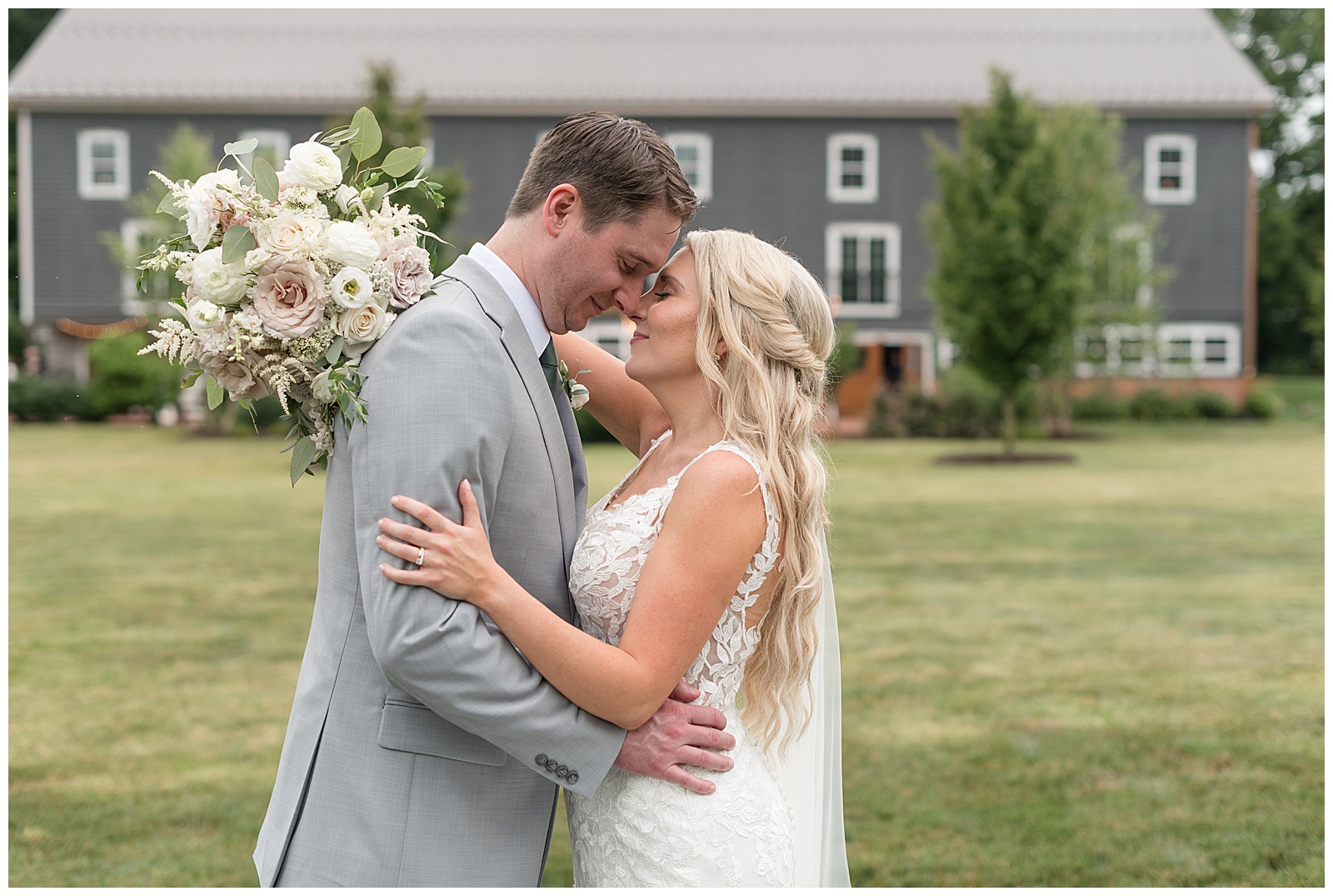 bride and groom resting their foreheads together outside by dark gray barn at historic ashland