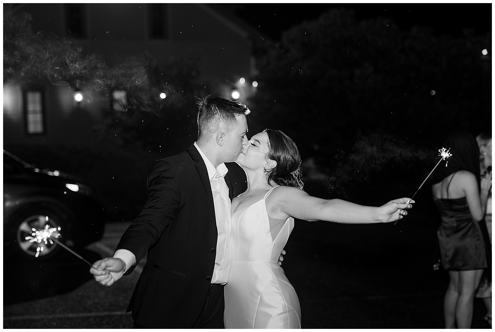 black and white photo of couple holding sparklers out as they kiss in the dark after wedding at cameron estate inn