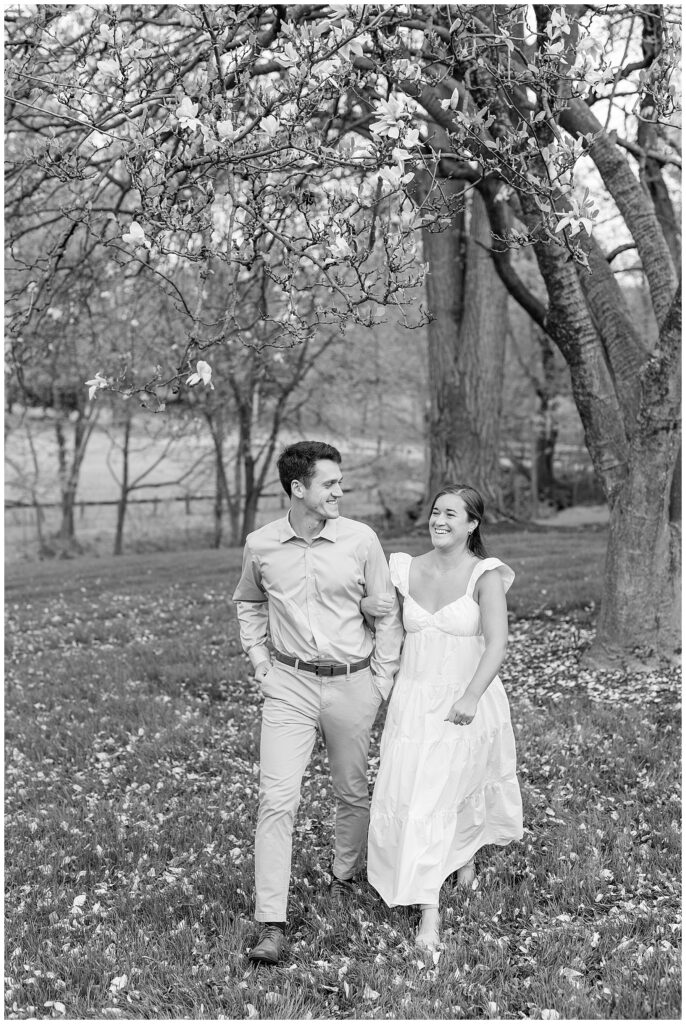 black and white photo of couple walking together in woods and smiling at historic ashland