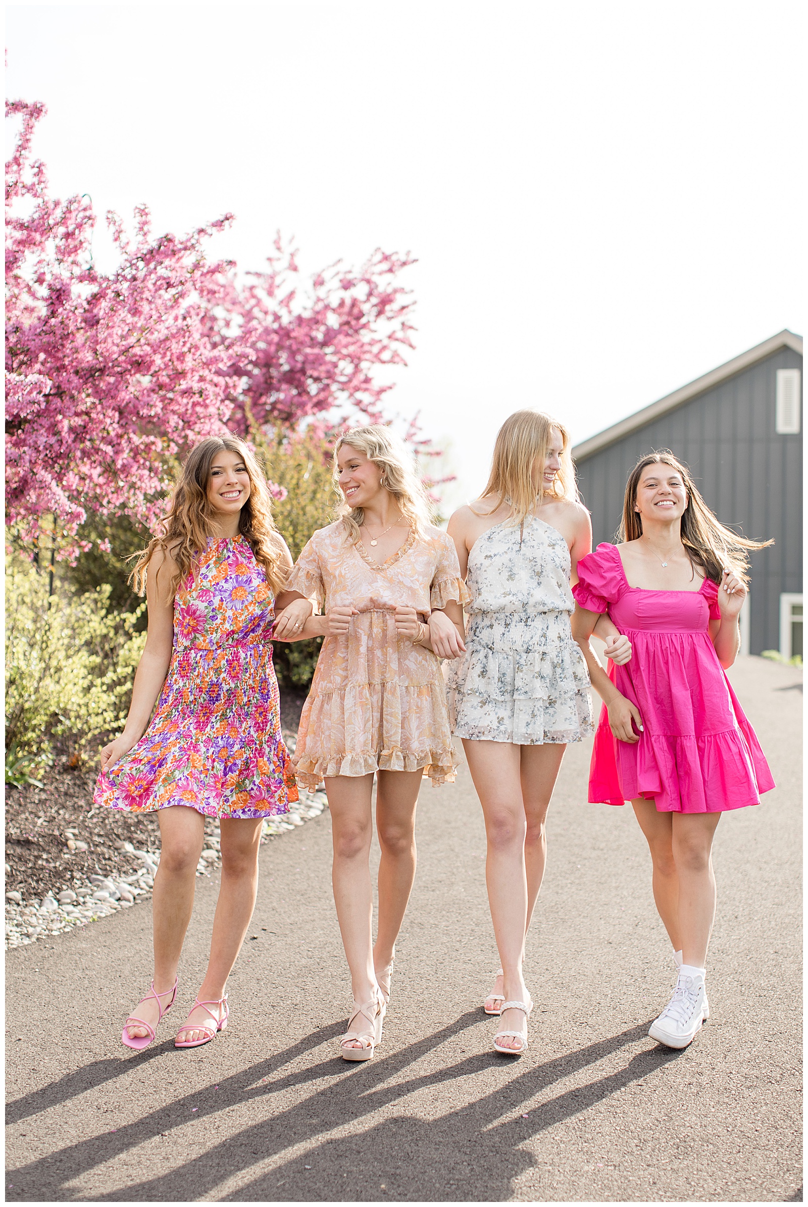 four senior girls with arms interlocked walking towards camera and smiling at overlook park