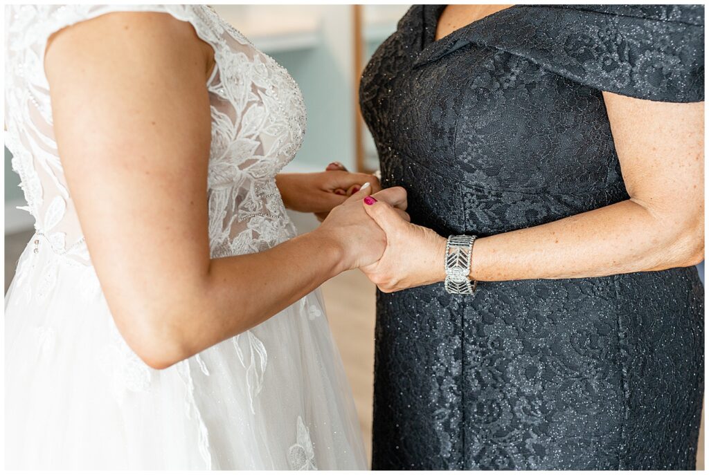 close up photo of bride and her mom standing close and holding hands in bridal suite at rivercrest golf club
