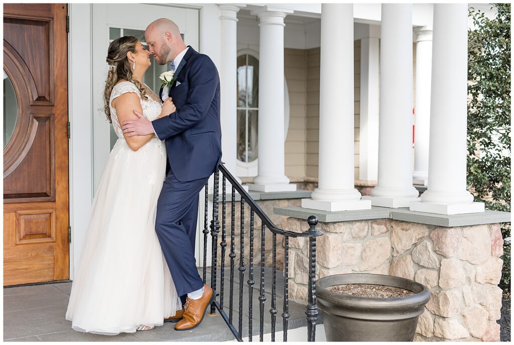 bride leaning against her groom who is leaning against wrought iron handrail as they almost kiss at rivercrest golf club