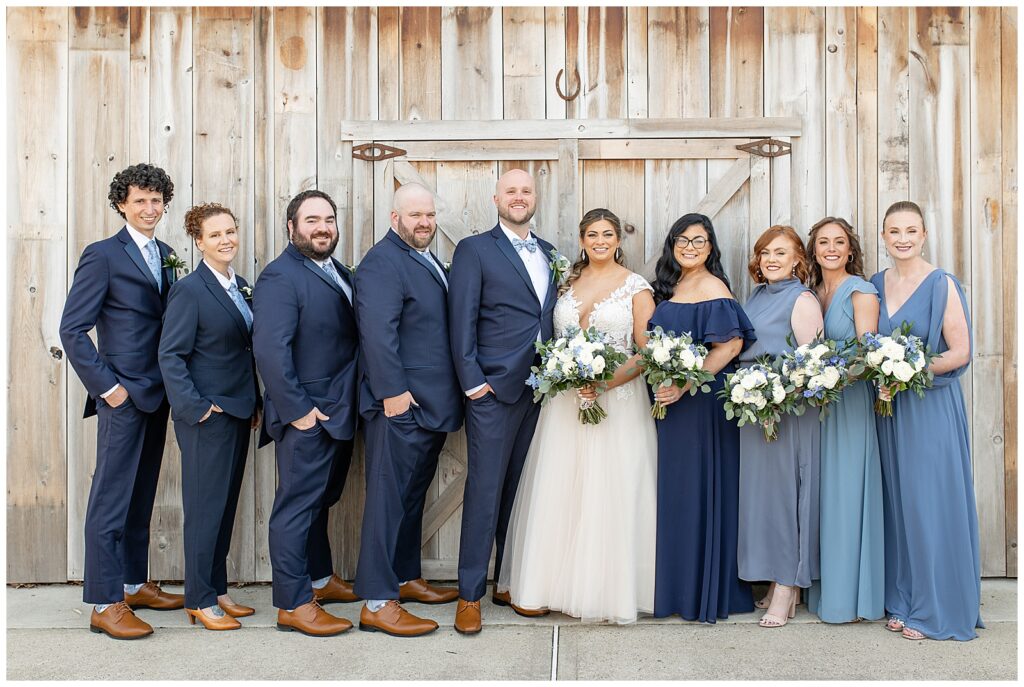 bride and groom with her bridal party in front of large wooden door at rivercrest golf club in pennsylvania