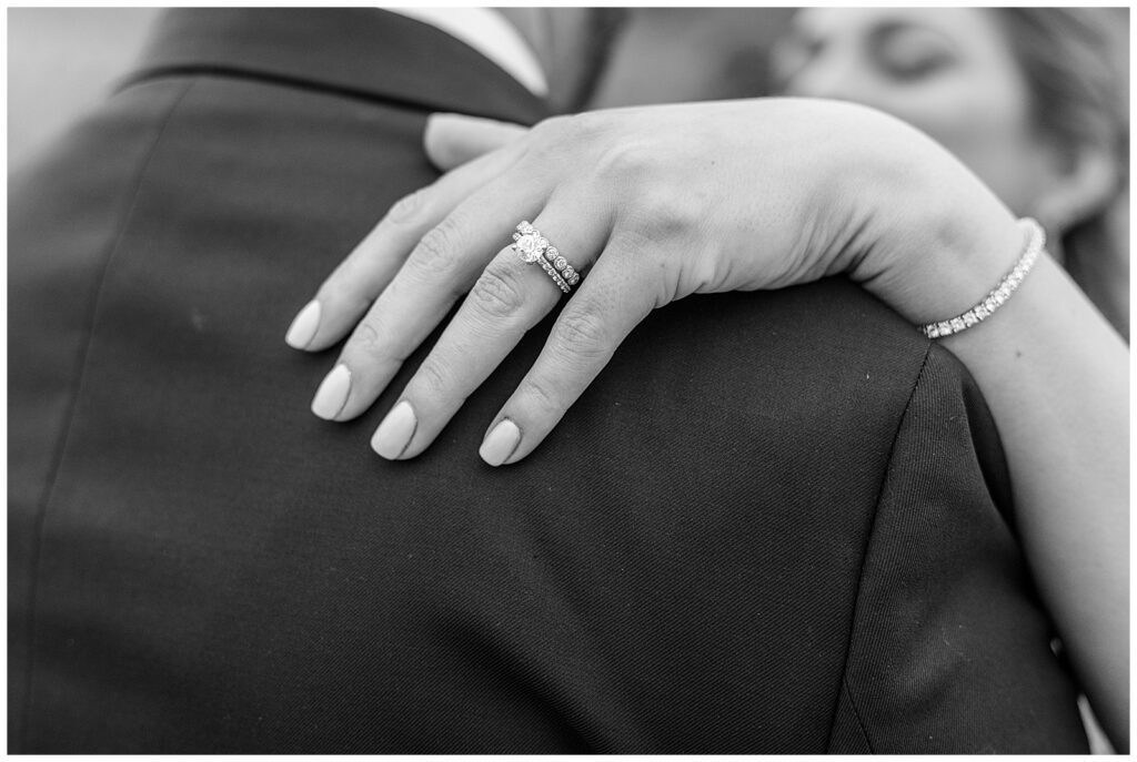 black and white photo of bride's hand on groom's shoulder showing off her rings in montgomery county pennsylvania