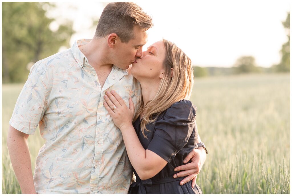 engaged couple kissing as woman rests her left hand on man's chest by wheat field in pennsylvania