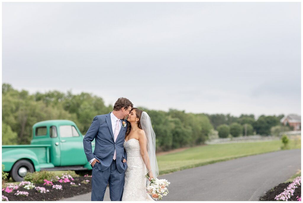 couple almost kissing along road with vintage green truck in background at promise farm in lancaster pennsylvania