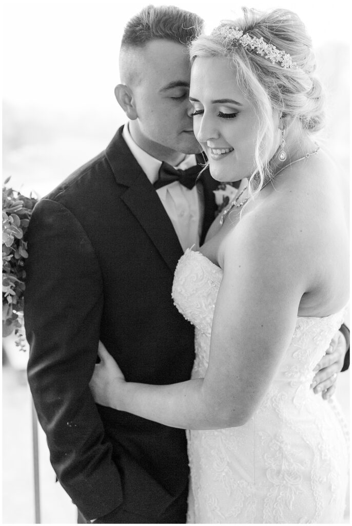 black and white photo of couple hugging tightly as groom rests his face against her right cheek at country club in bel air maryland