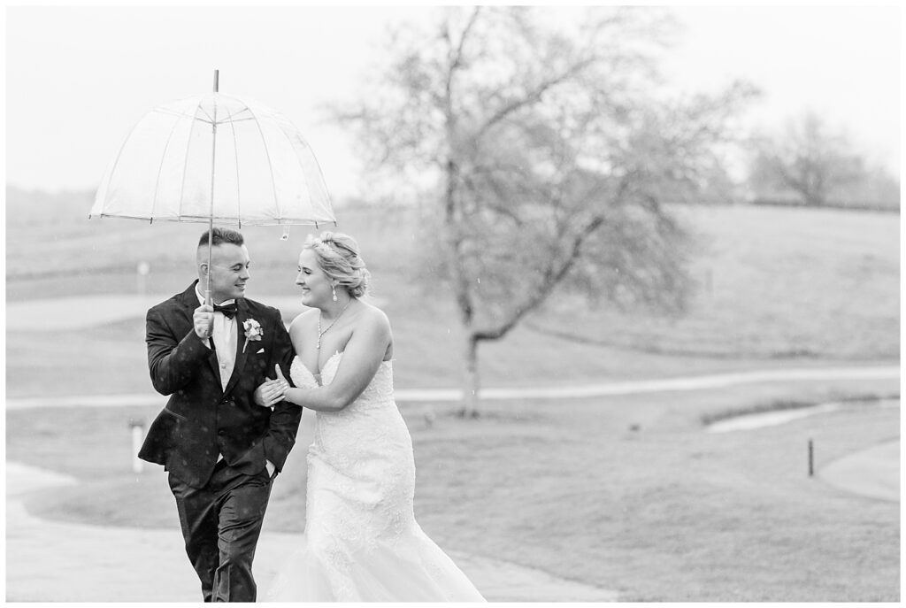 black and white photo of couple walking under umbrella on golf course at maryland golf and country club