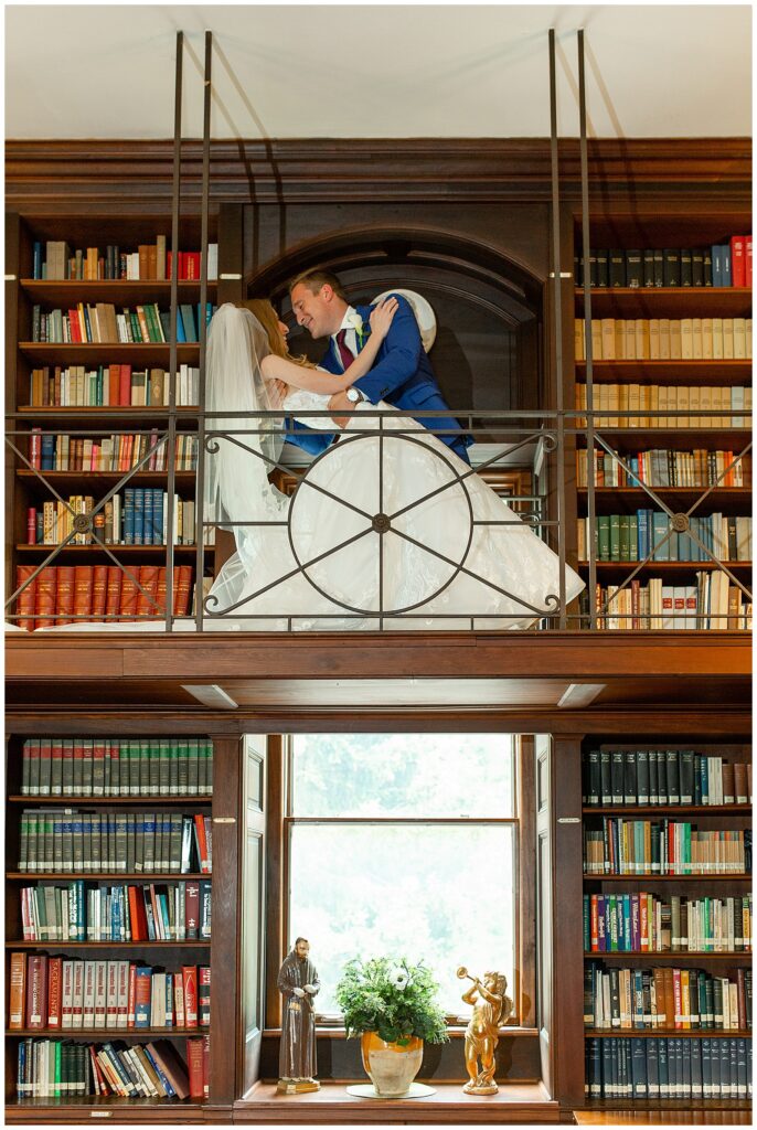 groom dipping his bride back inside upper level of colorful library at the shrine of saint anthony in maryland