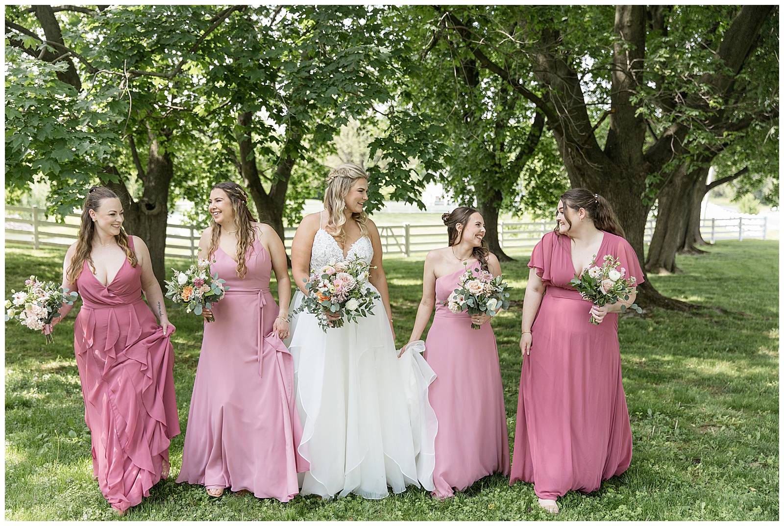 bride and her four bridesmaids looking at each other and walking towards camera outdoors at the barn at silverstone wedding venue