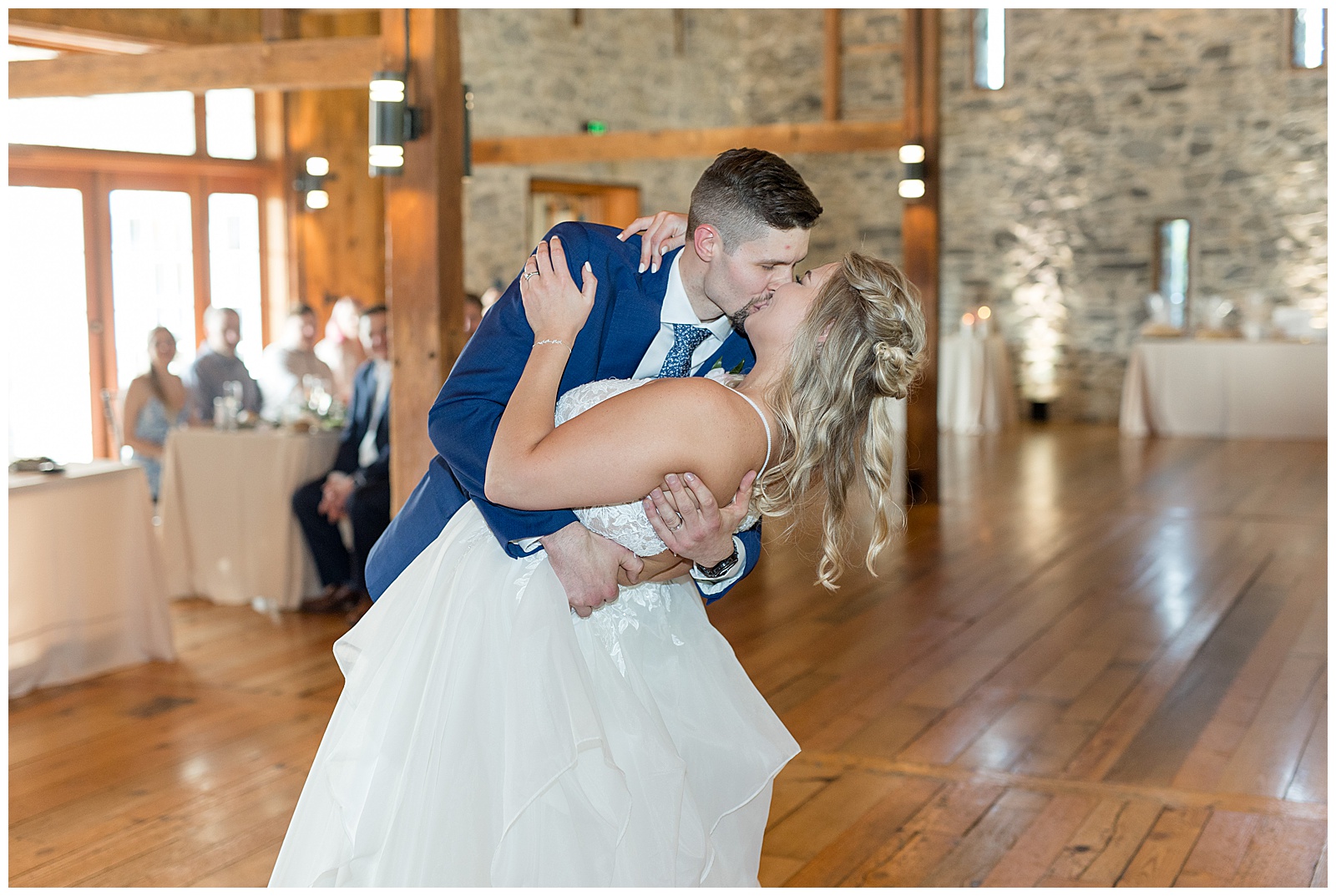 groom dips his bride back and kisses her during their first dance inside barn reception at the barn at silverstone