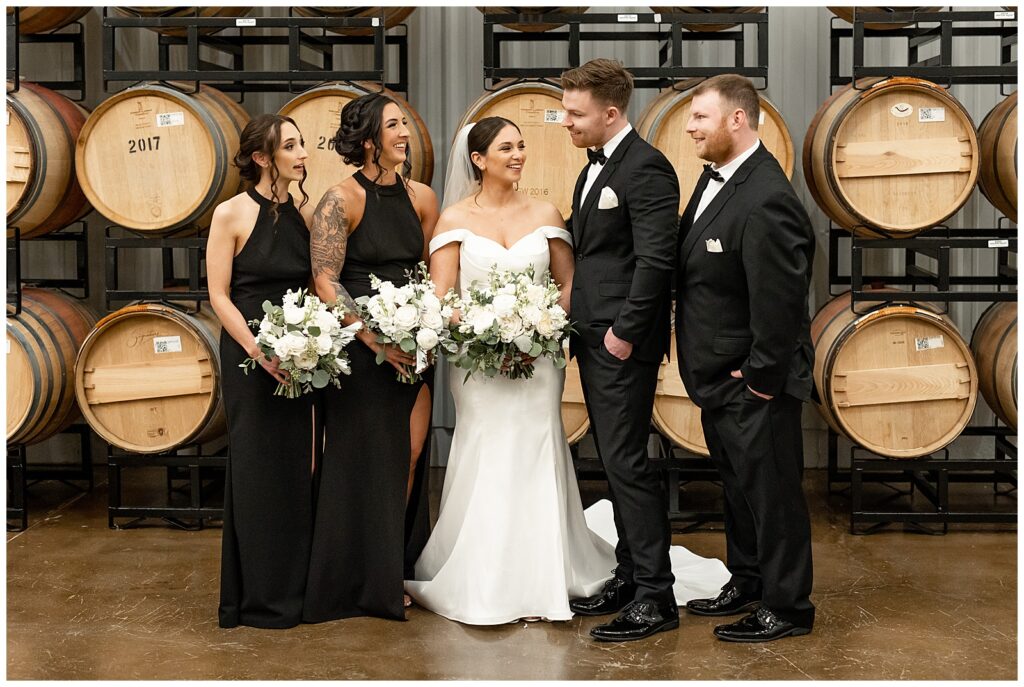 bride and groom with their small bridal party standing by large wooden barrels at folino estate winery