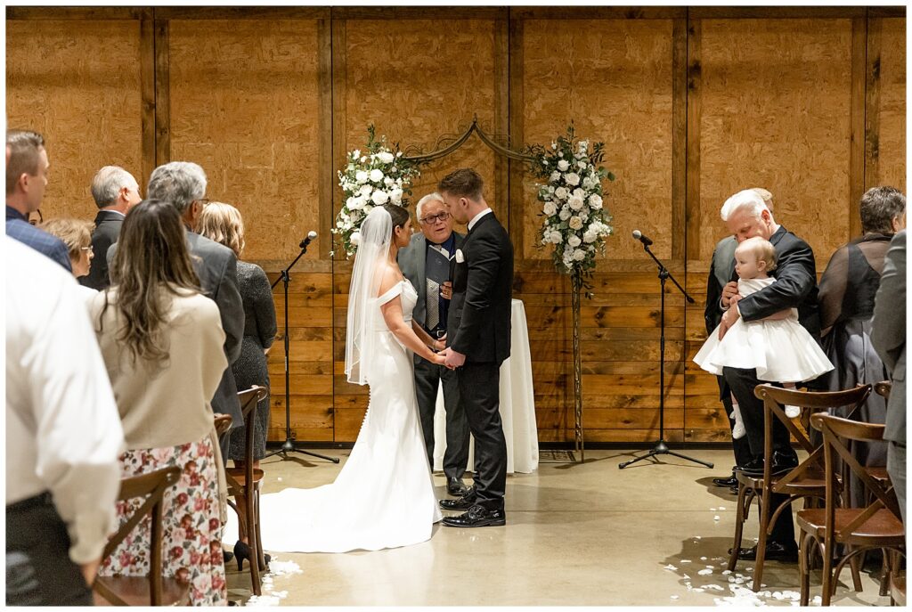 couple holding hands and facing each other during indoor wedding ceremony at folino estate