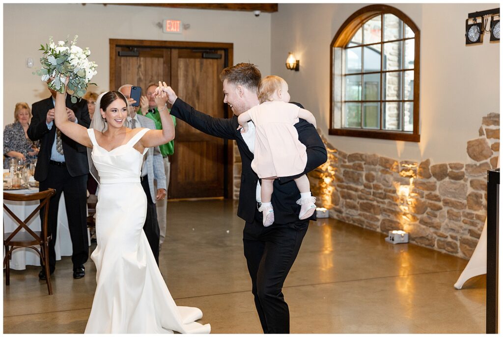 bride and groom making their grand entrance with groom holding their baby girl at folino estate