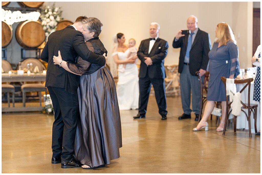 groom hugging his mom during their dance at reception as guests watch at folino estate