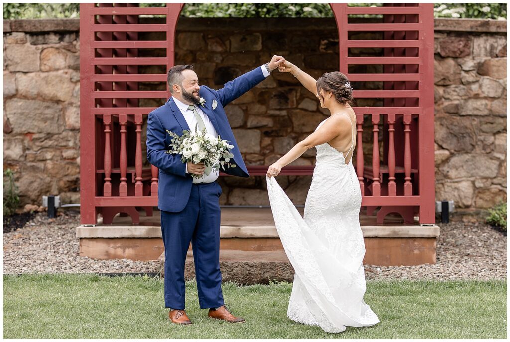 groom twirling his bride under his left arm holding her bouquet in his right hand at elizabeth furnace in lancaster county