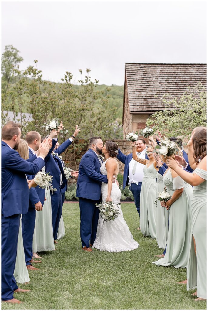 bride and groom kiss in between aisle created by their bridal party outdoors at elizabeth furnace