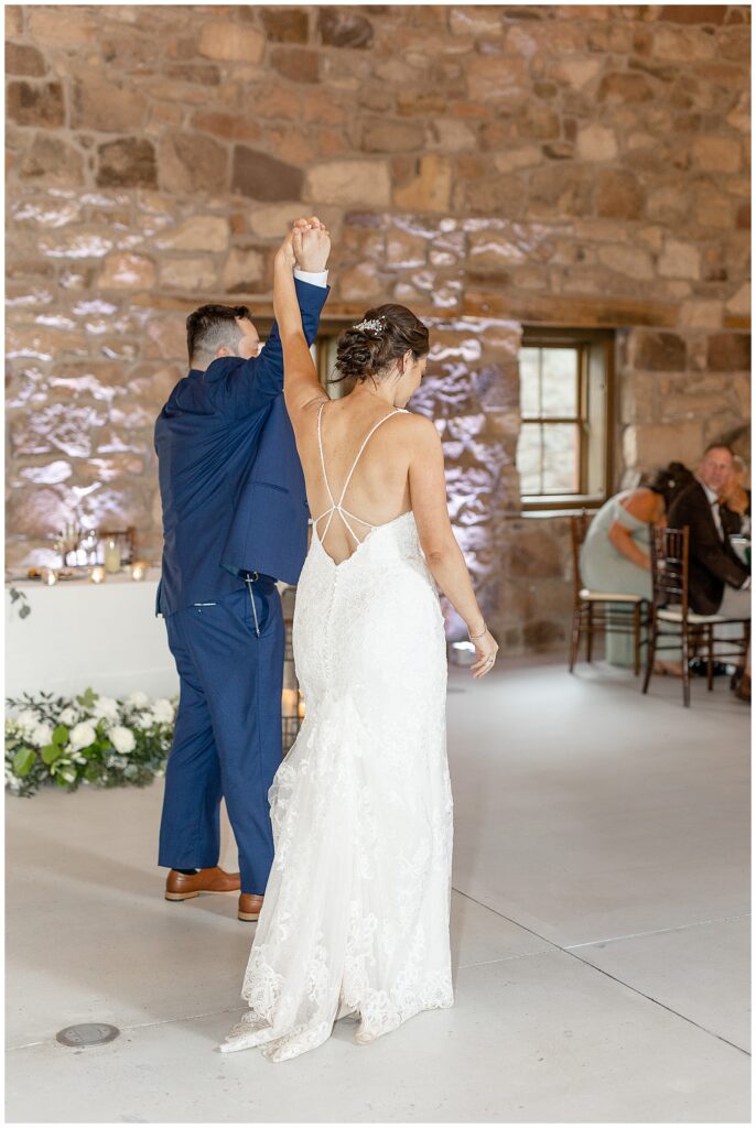 groom twirling his bride during their first dance inside stone building at elizabeth furnace