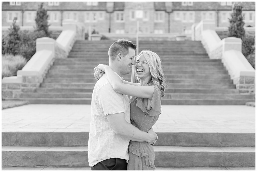 black and white photo of couple hugging as girl laughs by grand outdoor stairs at masonic village
