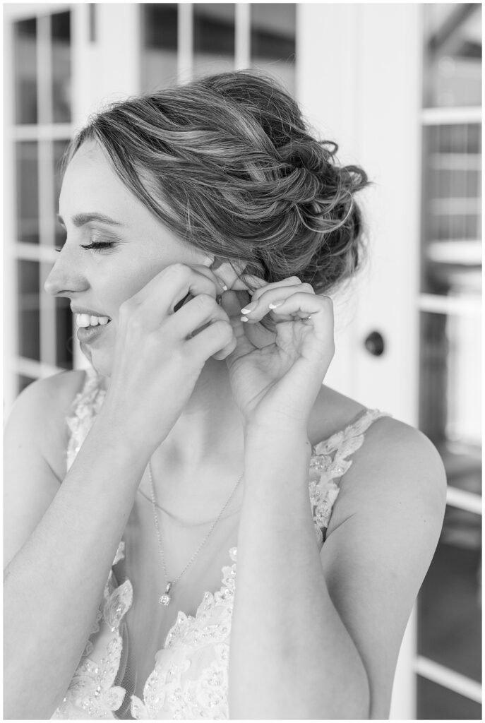 black and white photo of bride putting in her left earring in close up photo at barn at silverstone