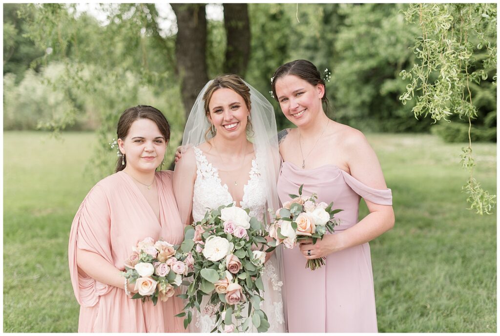 bride with her two bridesmaids who are wearing light pink gowns and all holding bouquets of pink and white flowers in lancaster pa