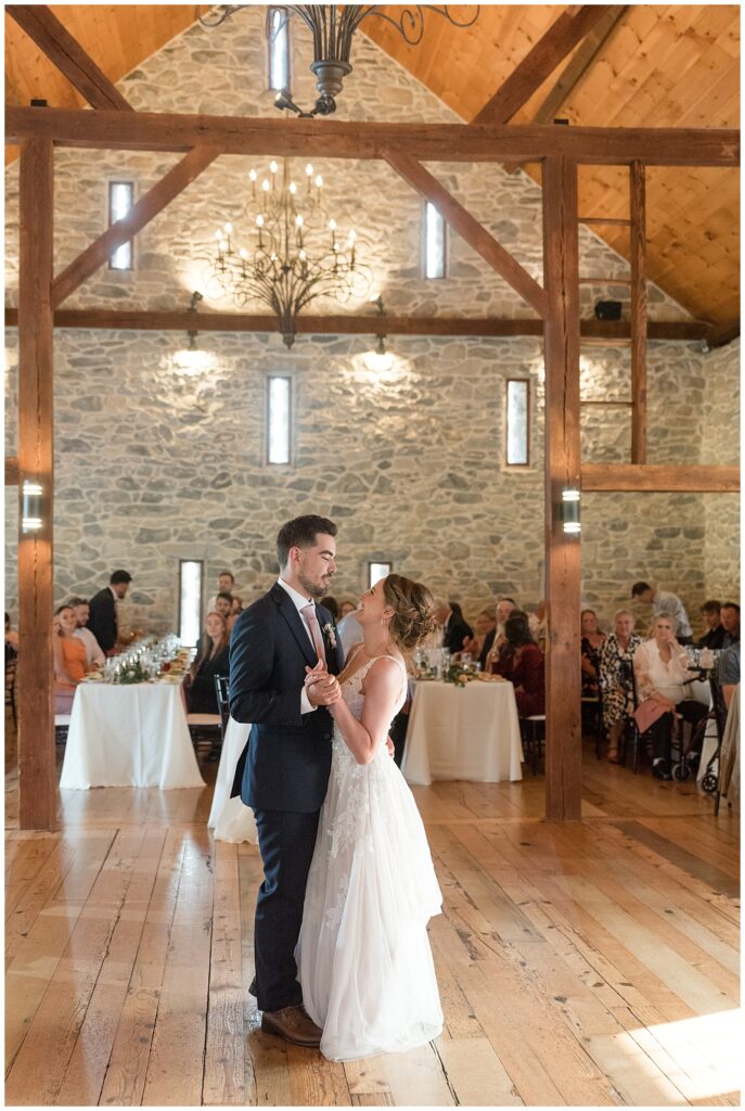 bride and groom sharing their first dance inside barn reception with guests watching in lancaster county