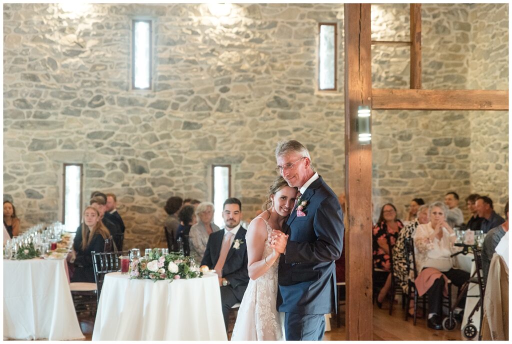bride dancing with her father and resting her left cheek against him inside barn venue in lancaster pa