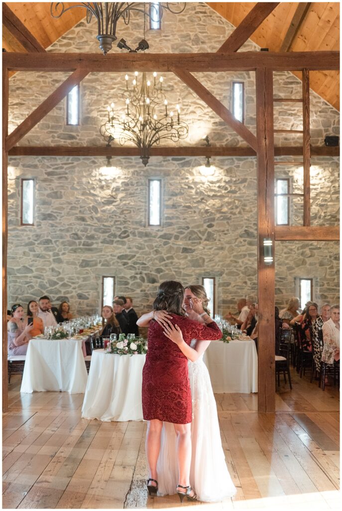 bride hugging her mom on the dance floor of barn reception at the barn at silverstone