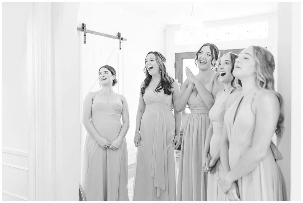 black and white photo of bridesmaids with big smiles as they see bride for the first time in her gown at historic ashland