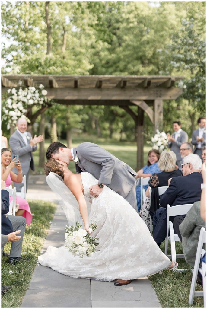 groom dips his bride back and kisses her in aisle as they leave outdoor wedding ceremony in wrightsville pennsylvania