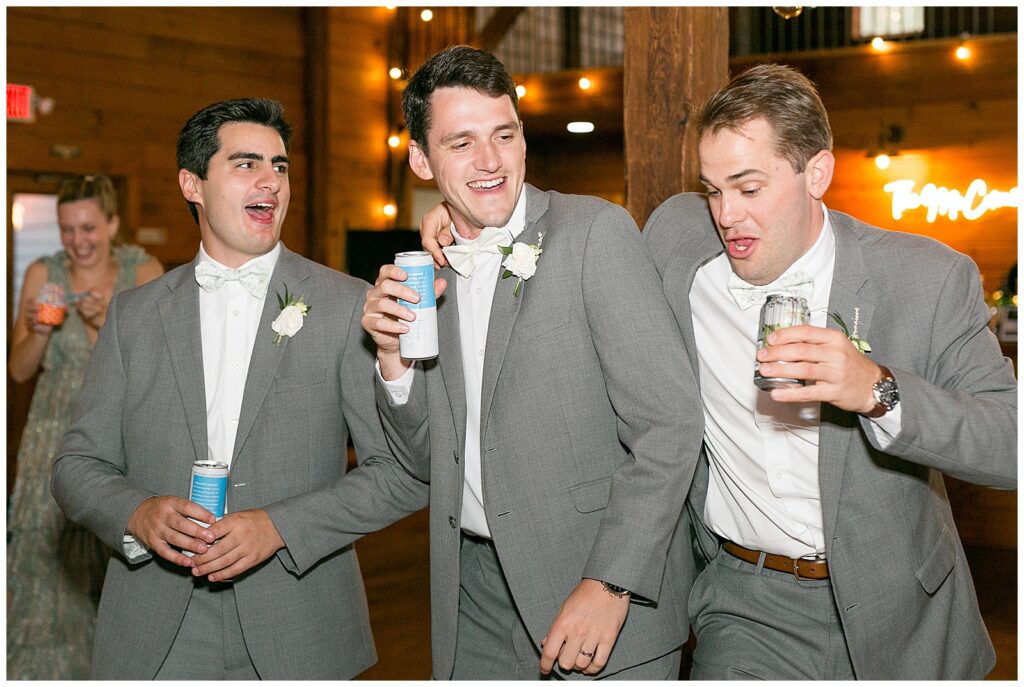 groom with two of his groomsmen holding drink cans and dancing during reception at historic ashland