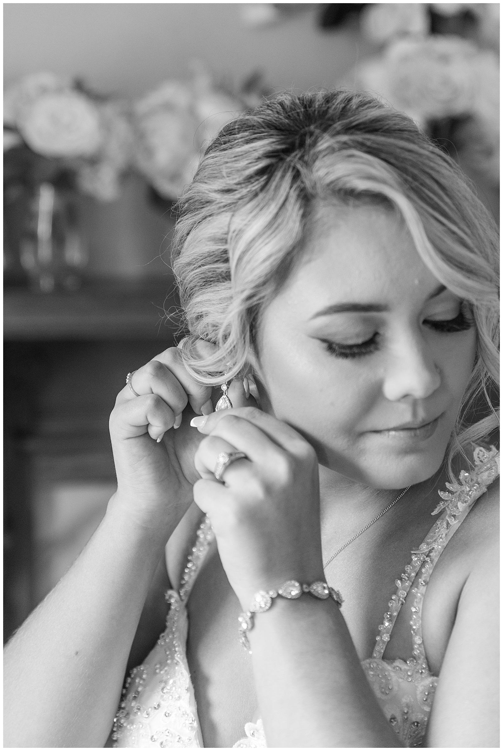 black and white photo of bride putting in her left earring and looking down at stoltzfus homestead and gardens