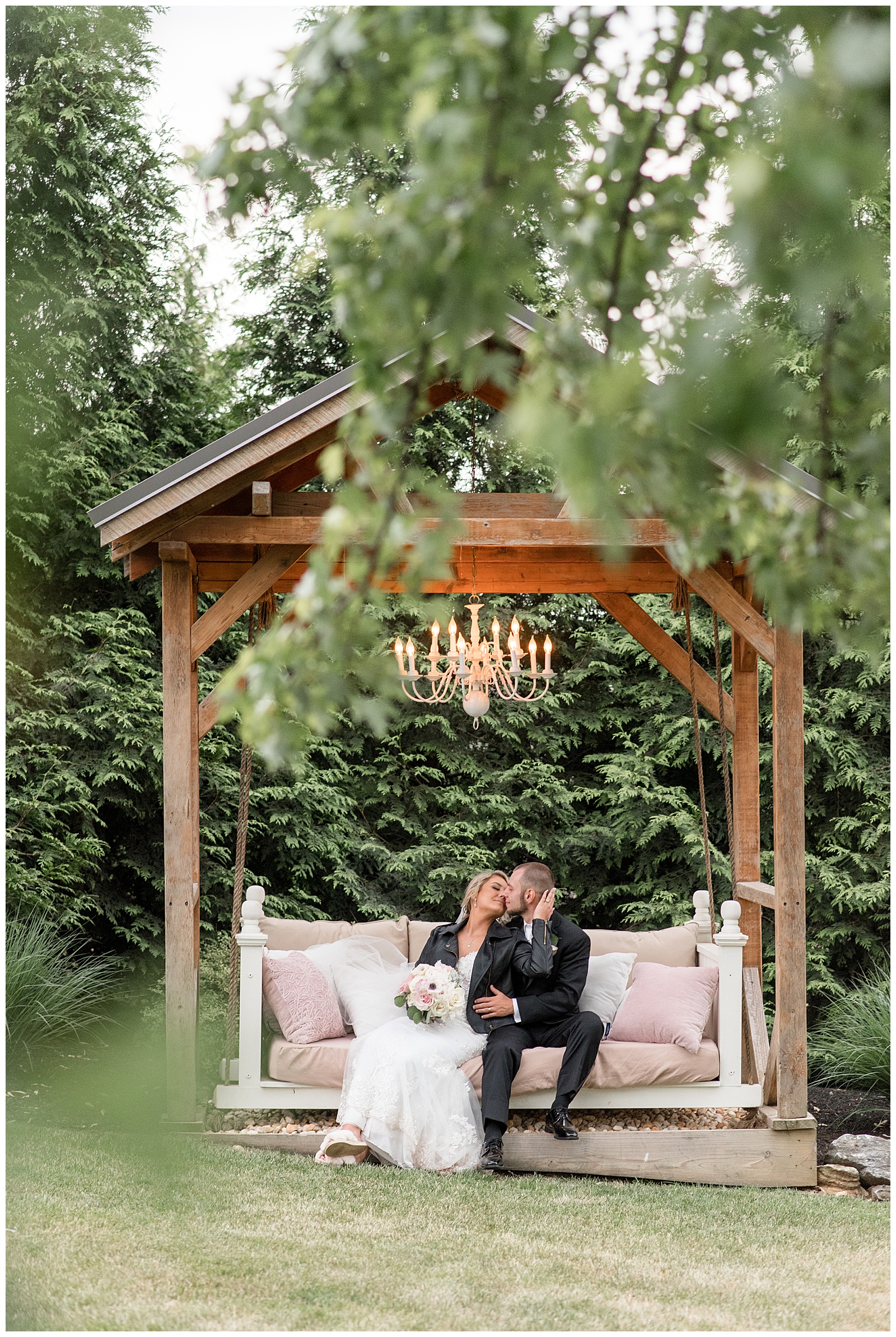 bride and groom sitting on wooden swing inside gazebo kissing at stoltzfus homestead and gardens