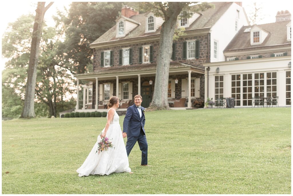 couple holding hands as groom leads bride in front yard of beautiful home estate at the inn at grace winery