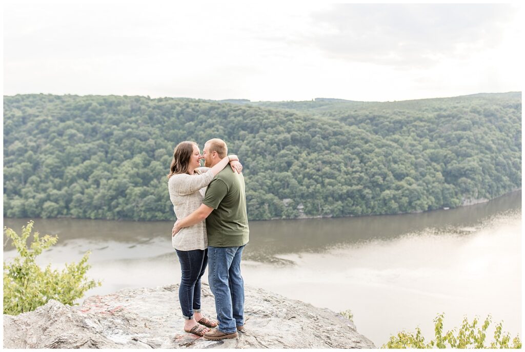 engaged couple hugging tightly atop large rock overlooking the susquehanna river at pinnacle point overlook