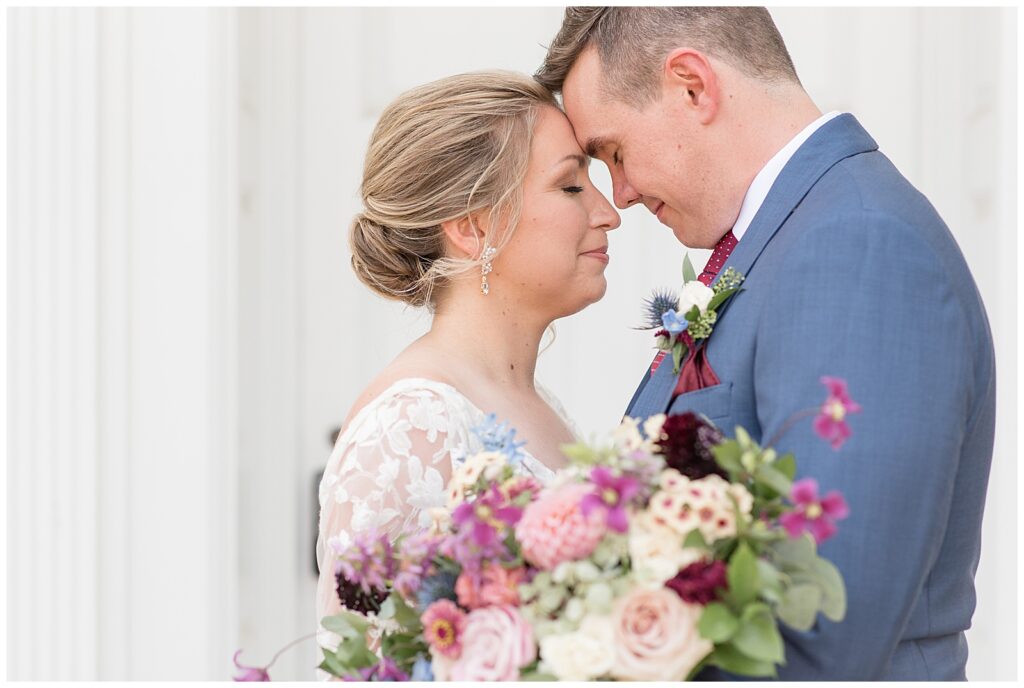 closeup photo of bride and groom touching foreheads with their eyes closed by white door at the barn at silverstone