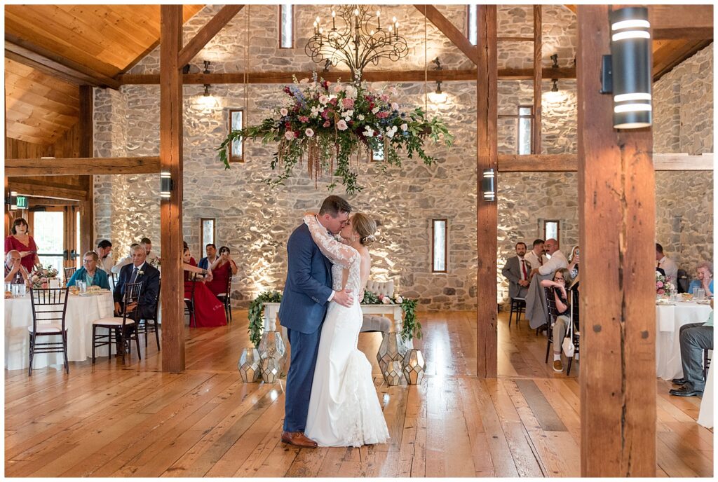 bride and groom sharing their first dance during barn wedding reception as guests watch at the barn at silverstone