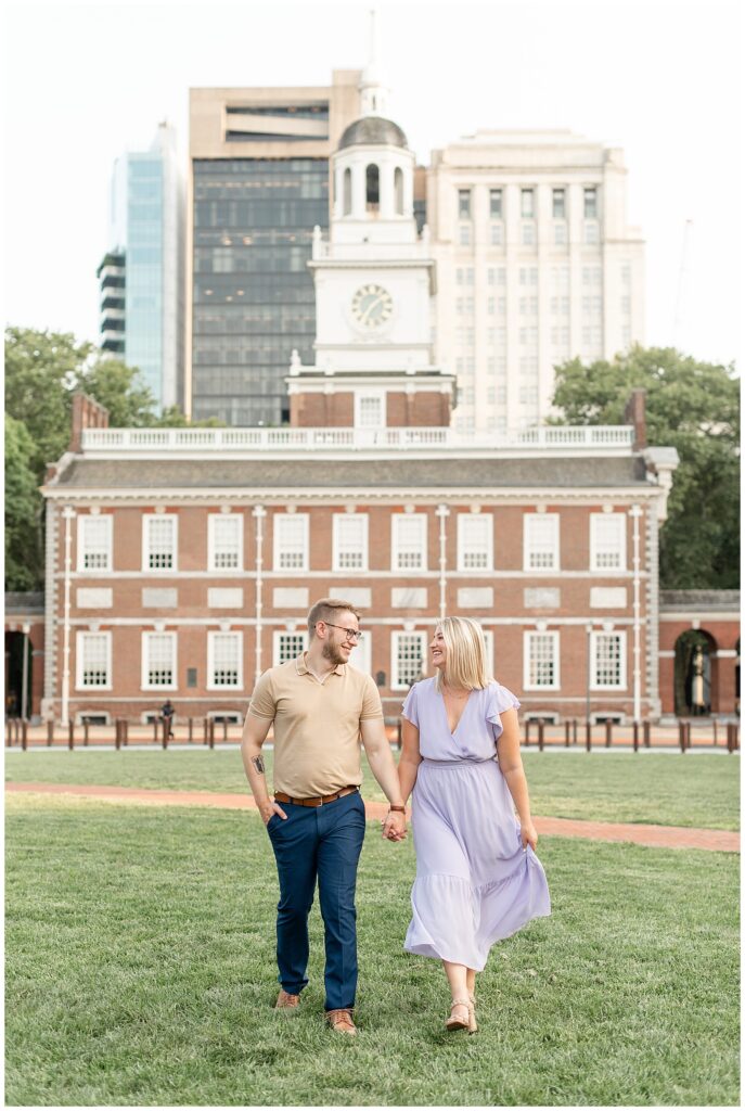 engaged couple holding hands as they look at each other in front of independence hall in philly