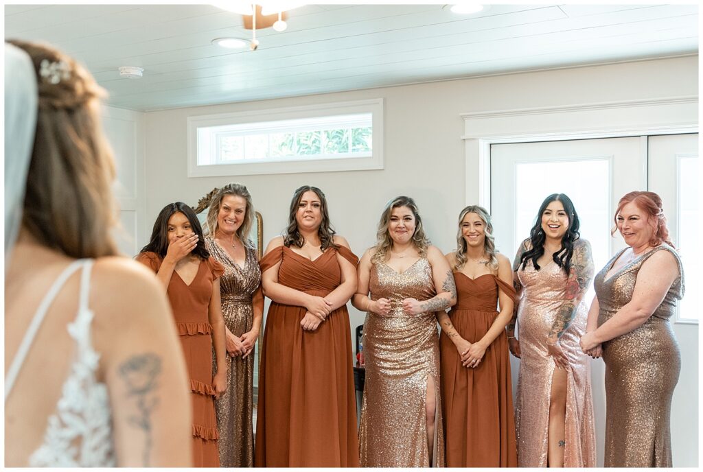 bridesmaids seeing bride for the first time in bridal suite in emotional moment and all wearing shades of rust dresses