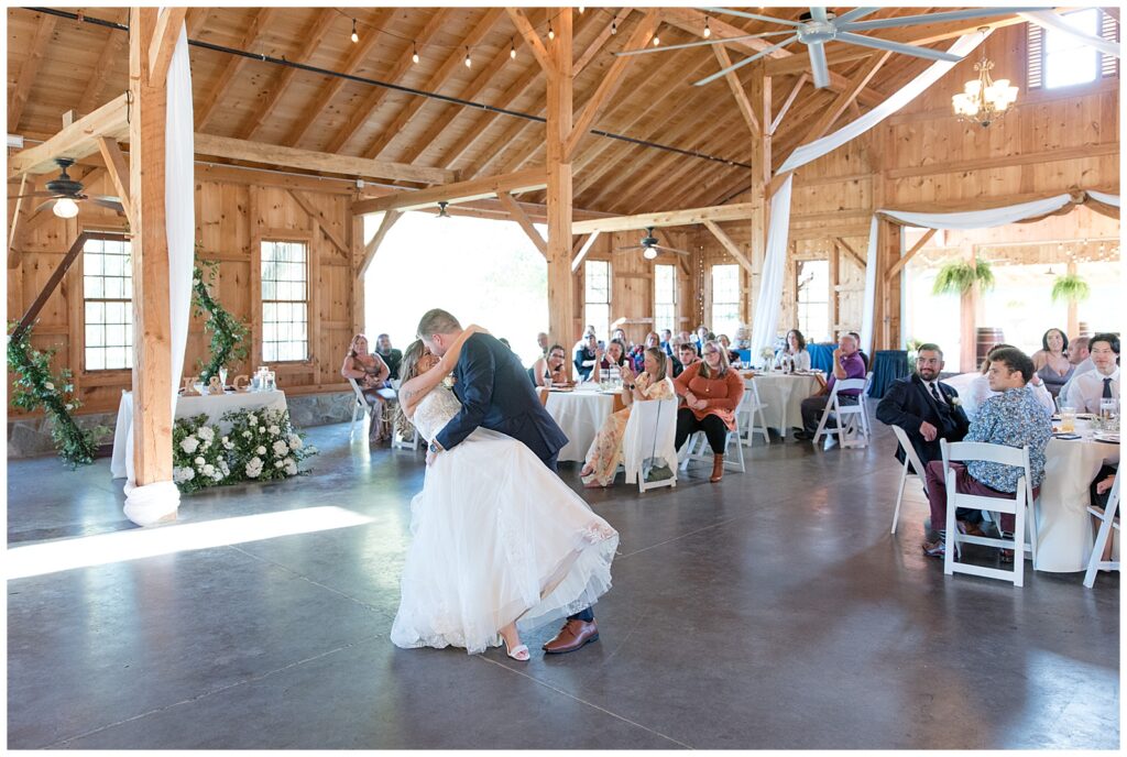 groom dipping his bride back and kissing her during first dance at reception at pond view farm