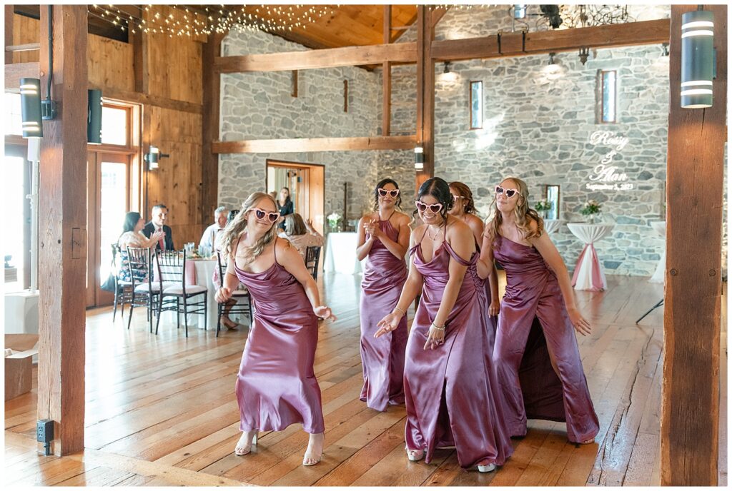 bridesmaids all wearing sunglasses and dancing during barn reception with guests watching at the barn at silverstone