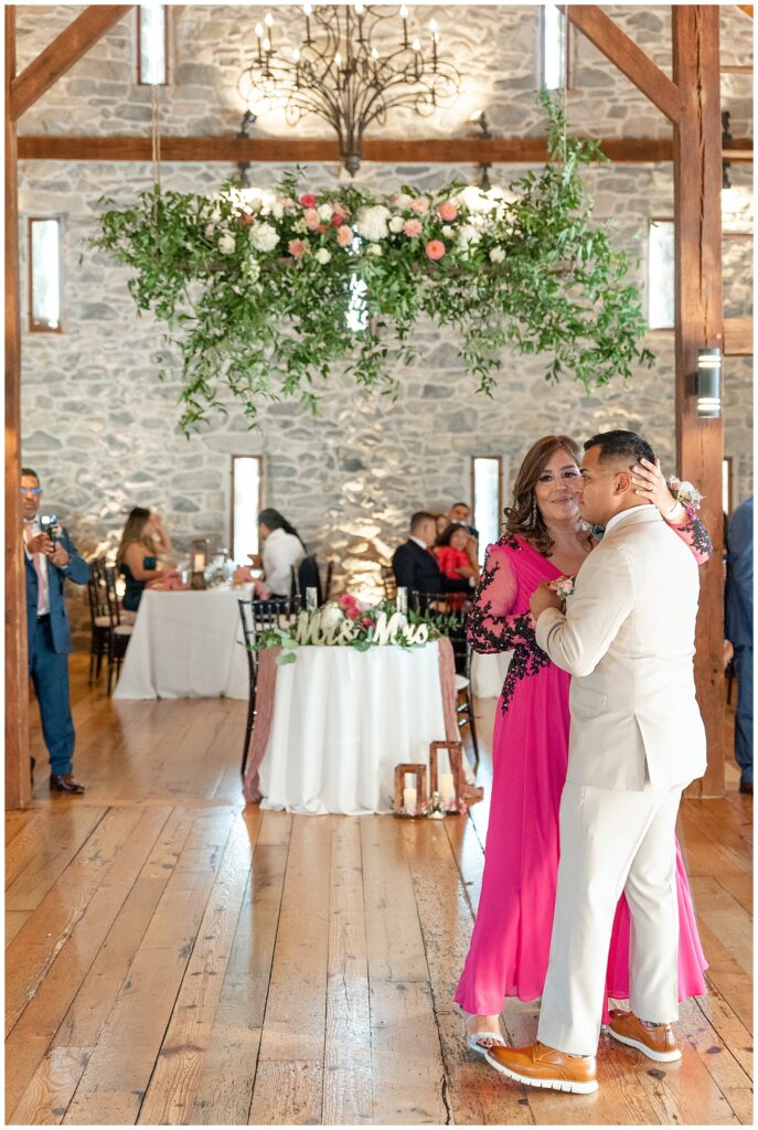 groom dancing with his mom who's wearing a bright pink dress during barn wedding reception at the barn at silverstone