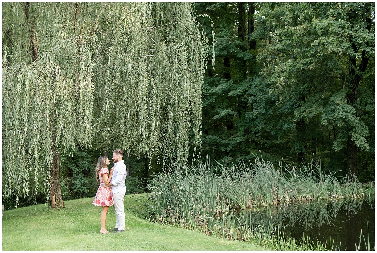engaged couple standing closely under willow tree with woman in pink dress and man in light colored outfit at Domaine Pterion