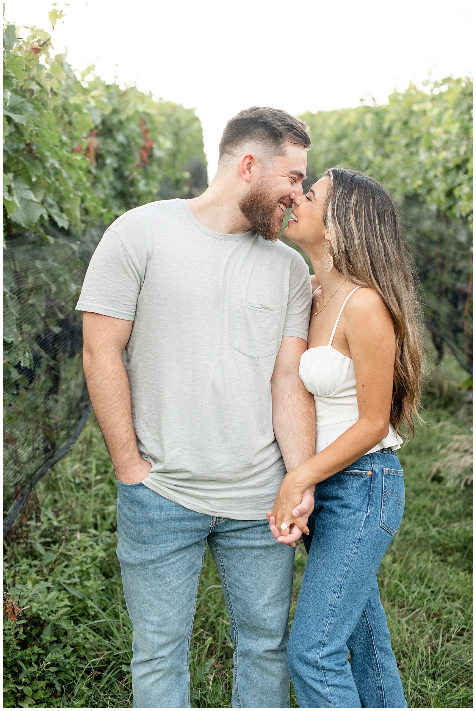 engaged couple touching noses and almost kissing in row of grape trees at vineyard at Domaine Pterion