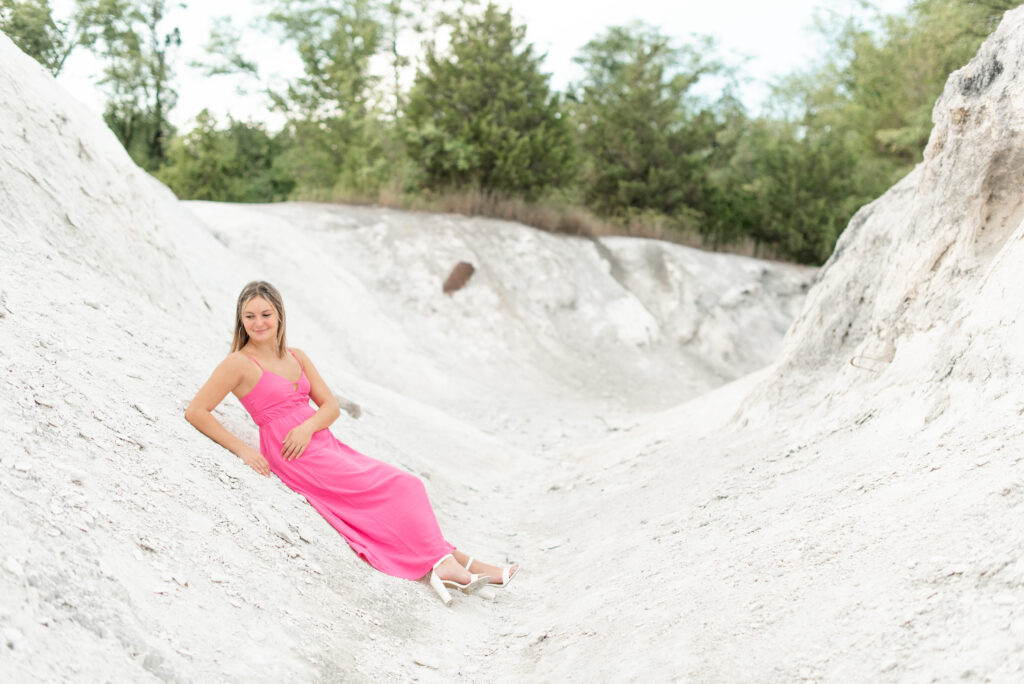 senior girl laying against large white rock with trees behind her at the white cliffs of conoy