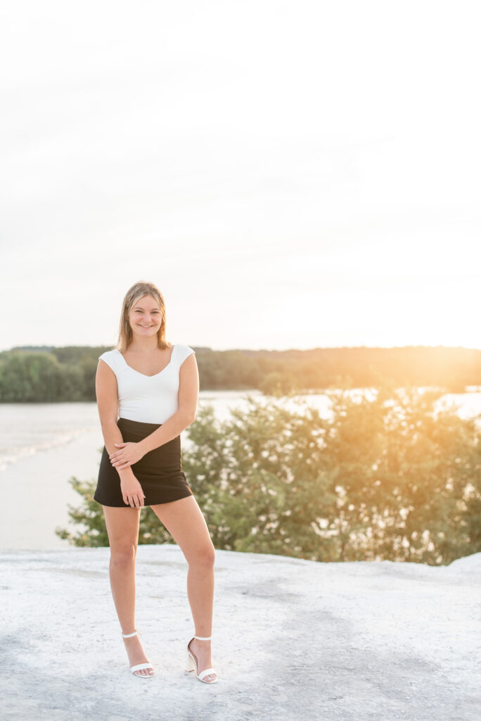 senior girl with left hand touching right forearm at sunset atop the white cliffs of conoy