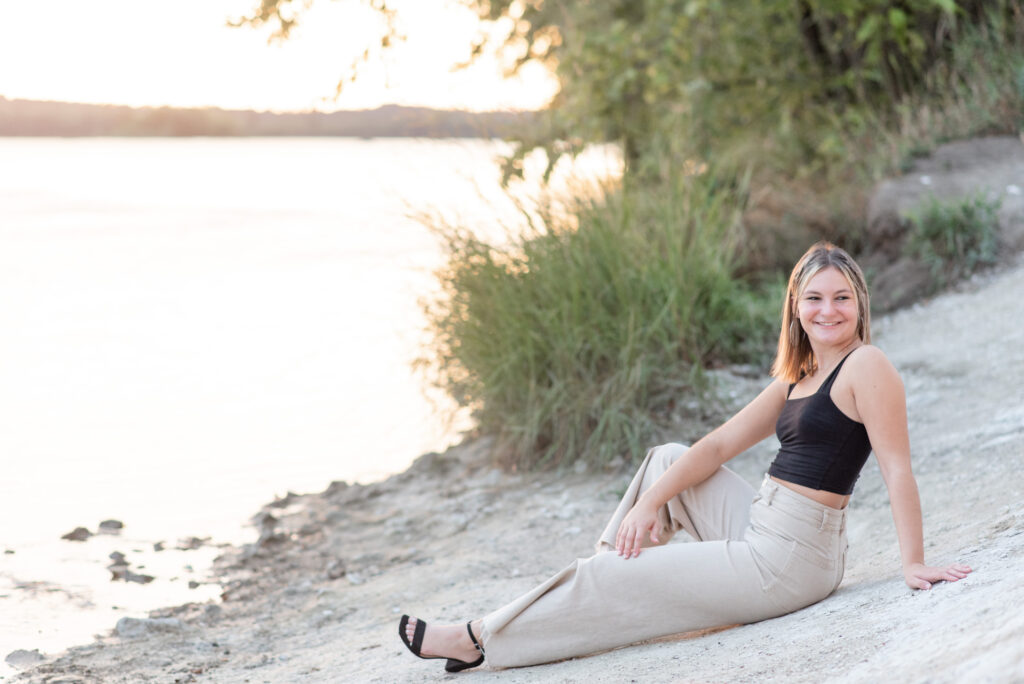 senior girl sitting on white rock with legs extended towards river at the white cliffs of conoy